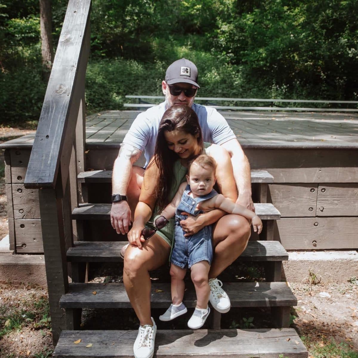 A young family sitting together on wooden steps outdoors